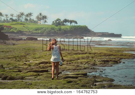 youngt woman on the beach exploring the cliffs of bali