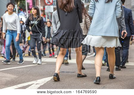 Hong Kong, China - December 6, 2016: asian sexy women in typical short skirt, walking fast by the street market Jardine's Crescent, Causaway Bay, looking for shopping.