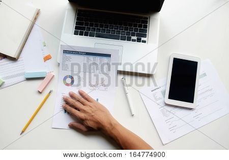 Asian business man manager analyzing datum in charts and typing on computer making notes in documents on the table in office vintage color selective focus. Business concept.