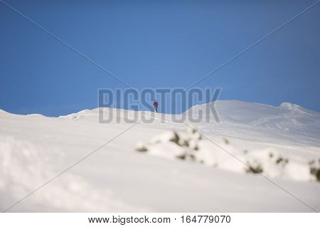 Panorama of snowy mountains. Man standing on top of the hill and preparing to go skiing. It is beautiful sunny day with blue sky.