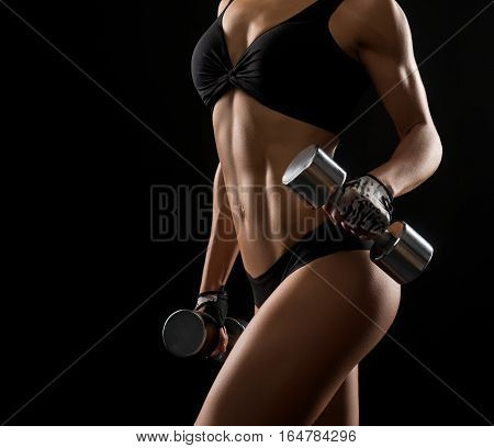 Unstoppable hardworker. Cropped closeup of s fitness woman with perfect strong muscular body posing with dumbbells in her hands