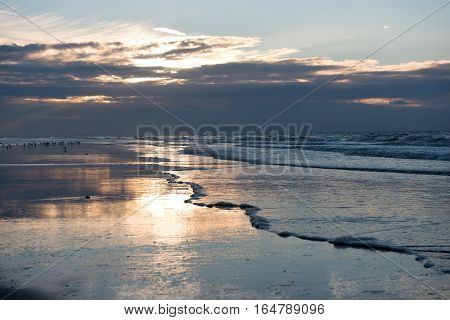 Sunset with reflection on the beach of Koksijde Belgium