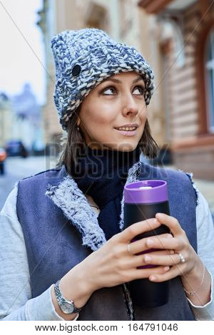 The girl with thermo cup, is walking through the old town