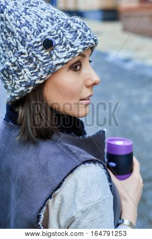The girl with thermo cup, is walking through the old town
