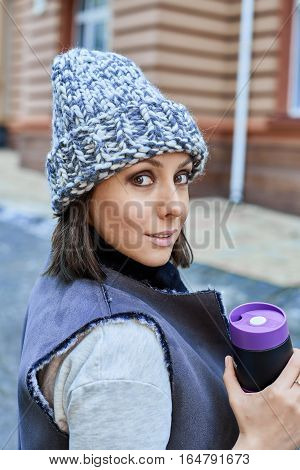 The girl with thermo cup, is walking through the old town