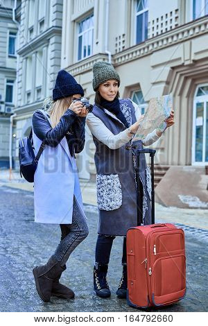 Two friends tourists choose attractions on the paper map