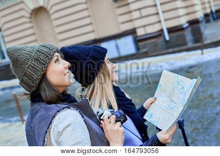Two friends tourists choose attractions on the paper map