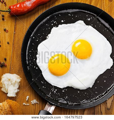 Traditional healthy easy quick breakfast meal made of two fried eggs served on a frying pan. International simple food top view.