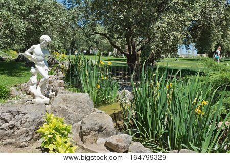 PARTENIT CRIMEA RUSSIA - JUNE 07.2015: Damaged statue of a boy catching a fish in olive grove Park 
