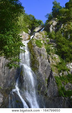 Aber Falls summer waterfall, portrait featuring trees, path, mountain side, clear blue sky, abergwyngregyn