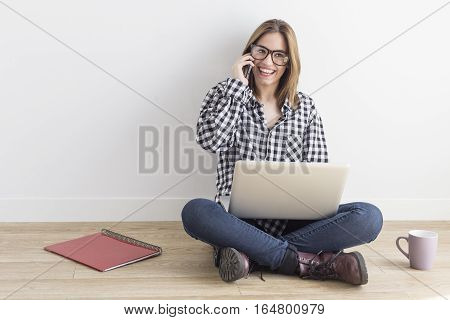 Young student working with computer and speaking with smartphone