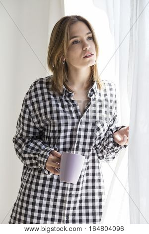 Melancholy girl having coffee looking out the window