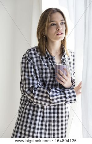 Melancholy girl having coffee looking out the window
