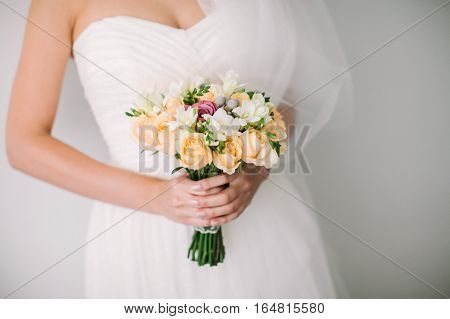 Beautiful woman in a wedding dress. Wedding bridal bouquet on a white background. The bride holds a fine wedding bouquet in hand.