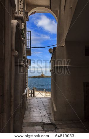 Vieste's historic center: view of the lighthouse from a arcade on the harbor..It' is located on the islet of Santa Eufemia opposite the town of Vieste.Italy.