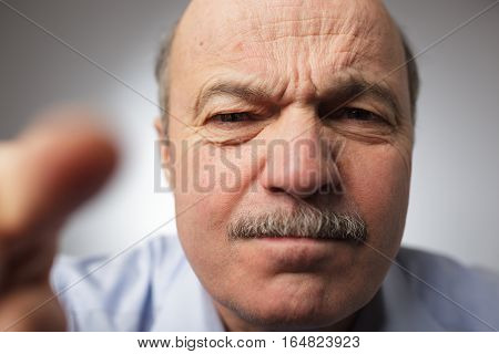 Elderly man dissatisfied frowns and looks sullenly. Poking his finger ahead