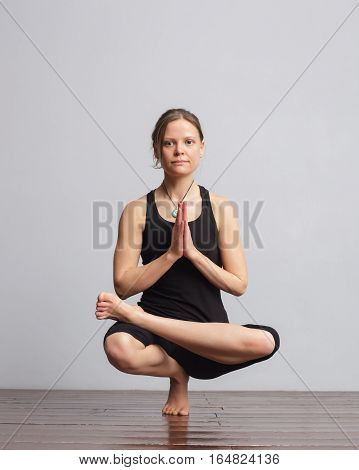 Girl making one foot balance yoga pose. On the pendant is written yogic symbol Aum