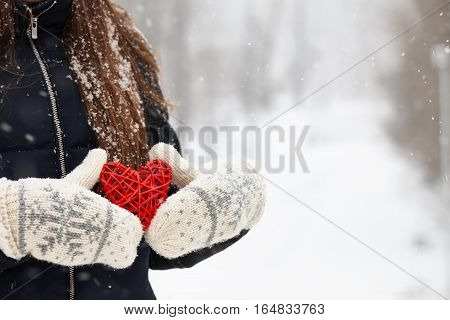 Woman holding red rattan heart on winter snow background, Valentines Day concept.