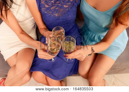 Top view of three women clinking with glasses of shampagne