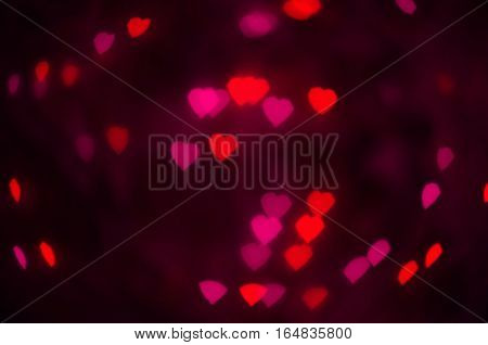 Pink and red hearts bokeh in dark texture for use in graphic design. Valentines style defocused lights background. St. Valentine's Day.