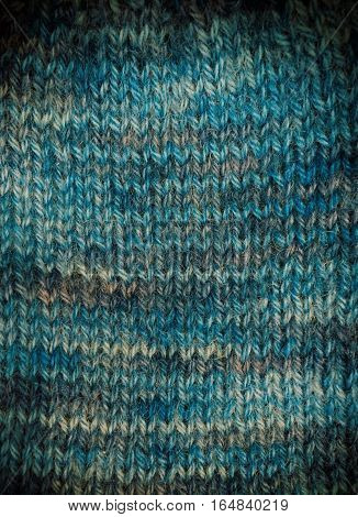 Handknitted background in various shades of blue with a vignette. Space for text.