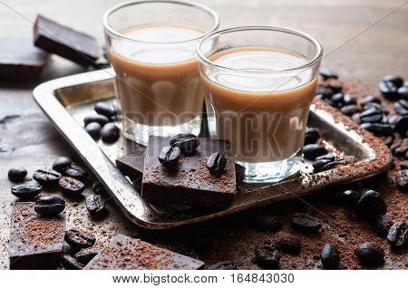 Coffee liqueur shot glasses with homemade baileys roasted coffee beans and chocolate selective focus toned image