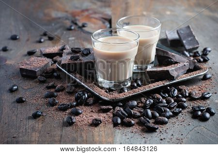Coffee liqueur shot glasses with homemade baileys roasted coffee beans and chocolate selective focus toned image