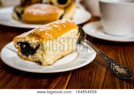 Baked sweet buns with poppy and coffee on wood table
