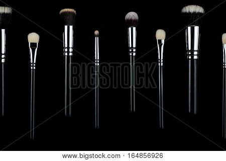 Makeup brushes lying on a black background