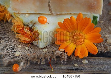 Natural handmade soap with calendula and sea-buckthorn on rustic wooden background