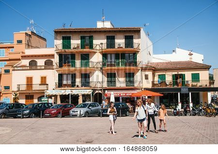 Alcudia Mallorca Spain - May 23 2015: Family of tourists walking along at historical town part of Alcudia with its traditional house and cafe. Carles V square area.