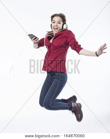 Happy girl jumping with headphones over white background