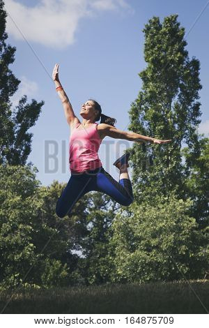 Beautiful woman doing jumping exercises in nature
