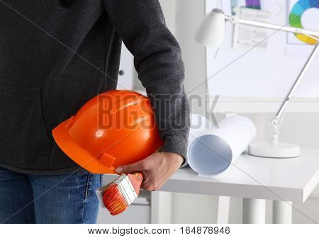Man architect wearing suit holding helmet with brush.