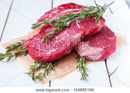 Raw meat with rosemary on a wooden background