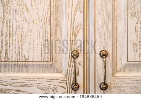 Close-up of vintage wooden kitchen cabinet or cupboard with metal handles as background.