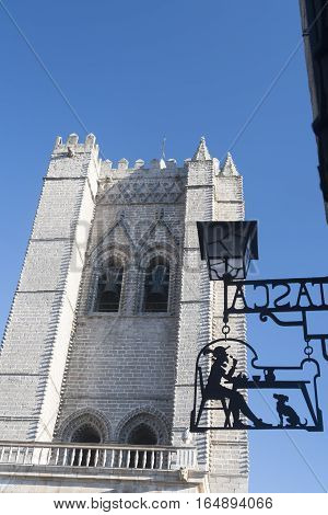AVILA, SPAIN - JULY 23, 2016: Avila (Castilla y Leon Spain): historic cathedral belfry and a shop sign