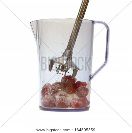 Electric blender and strawberries with sugar inside jug before mixing isolated on white background closeup