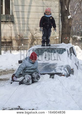 Bucharest Romania January 13 2008: Children are playing on a car covered in snow in a sunny cold day. Meteorologists announced temperatures lower than normal for this period.