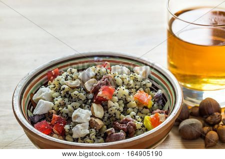 Christmas kutia and uzvar. Traditional ukrainian cereal wheat porridge with raisins, nuts, poppy seeds, honey and candied fruit in earthenware bowl with dried fruit drink on natural wood table