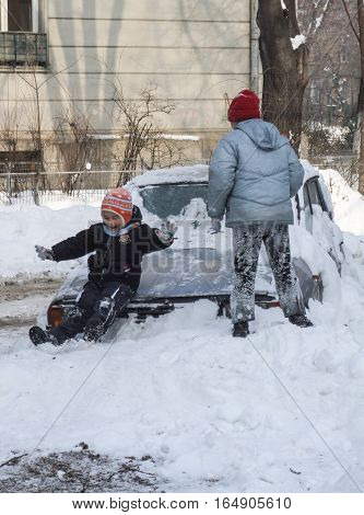 Bucharest Romania January 13 2008: Children are playing on a car covered in snow in a sunny cold day. Meteorologists announced temperatures lower than normal for this period.