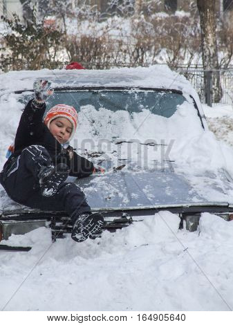 Bucharest Romania January 13 2008: Children are playing on a car covered in snow in a sunny cold day. Meteorologists announced temperatures lower than normal for this period.