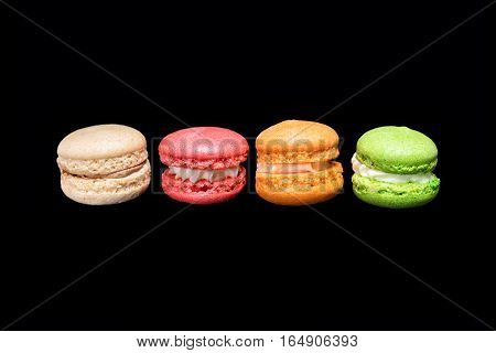 Multicolored macaroons isolated on black background falling or flying in motion. Traditional french dessert macarons.