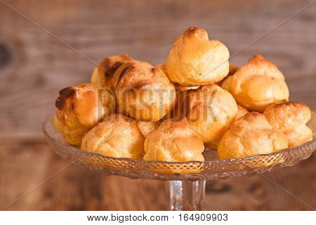Group of sweet cream puffs on glass tray.