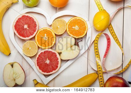 Fruits in heart and centimeter on a white background