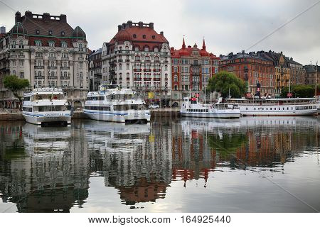 STOCKHOLM SWEDEN - AUGUST 20 2016: Many people walk and visit on Strandvagen street on Ostermalm distric with touristic sightseeing boats in Stockholm Sweden on August 20 2016.