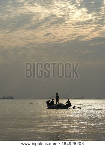Four people in a boat against the setting sun on the ocean