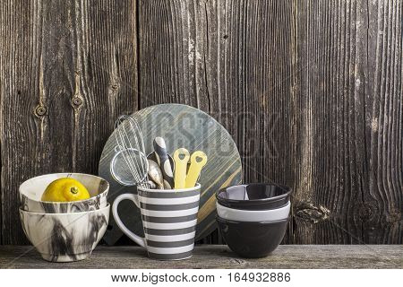 Cookware in gray and tools on a wooden kitchen shelf in the background rustic wooden wall. The horizontal design