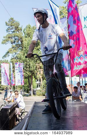 KAZAKHSTAN ALMATY - AUGUST 28, 2016: Urban extreme competition, where the city athletes compete in the disciplines: skateboard, roller skates, BMX. Bmx stunt performed at the top of a mini ramp on a skatepark.