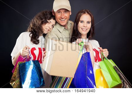 studio shot of three young people enjoying a sale event - and if you cant join them at the mall, mr. deliveryboy will bring you the stuff right to your door